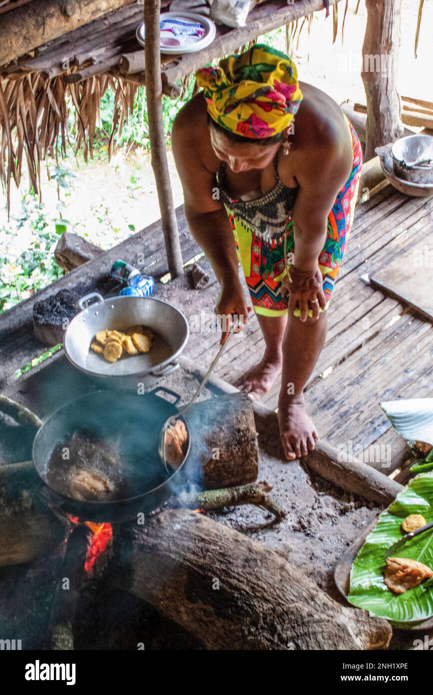 Eine einheimische Embera-Frau, die in einer traditionellen Küche in einer Strohhütte in einem Embera-Dorf in Panama Essen zubereitet. Stockfoto