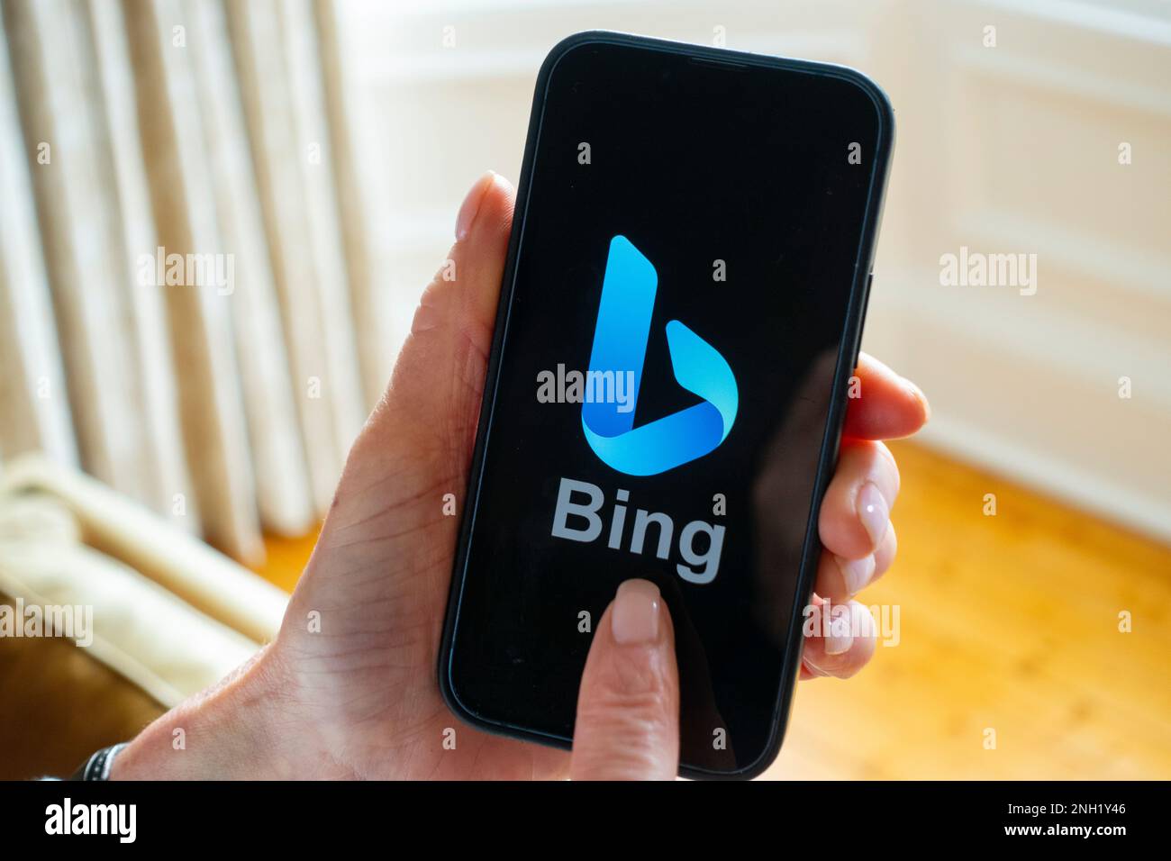 Person hält Mobiltelefon und zeigt das neue Microsoft ChatGPT OpenAI Bing Suchmaschinenlogo auf dem Bildschirm an Stockfoto