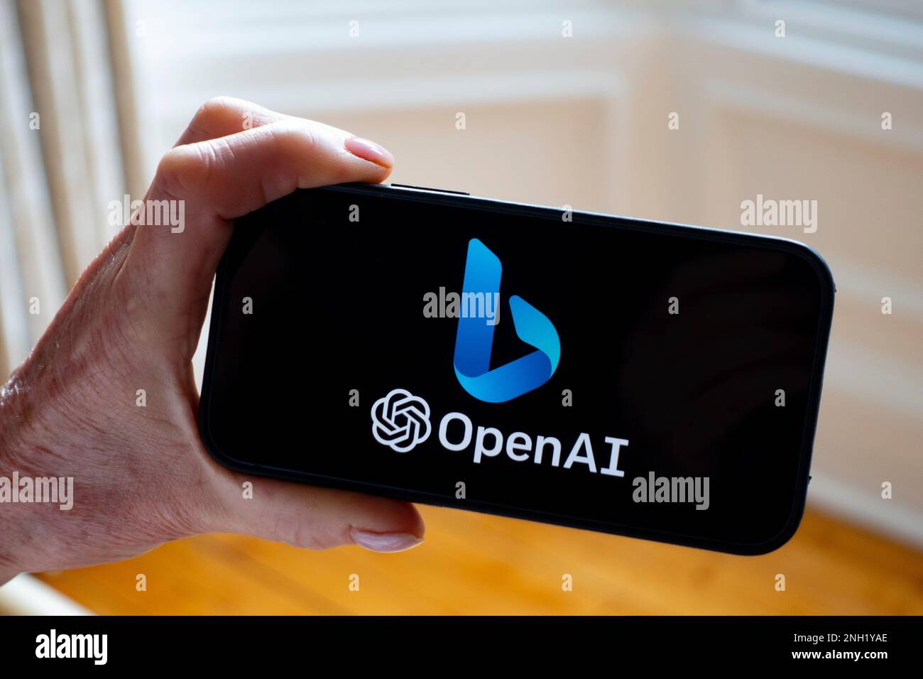Person hält Mobiltelefon und zeigt das neue Microsoft ChatGPT OpenAI Bing Suchmaschinenlogo auf dem Bildschirm an Stockfoto