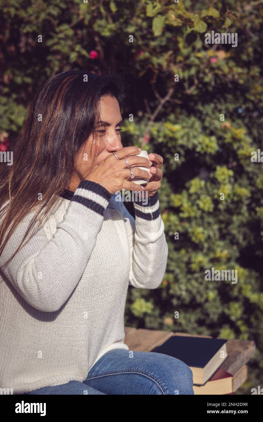 Moment der Ruhe: Latina-Frau trinkt Kaffee im Garten Stockfoto