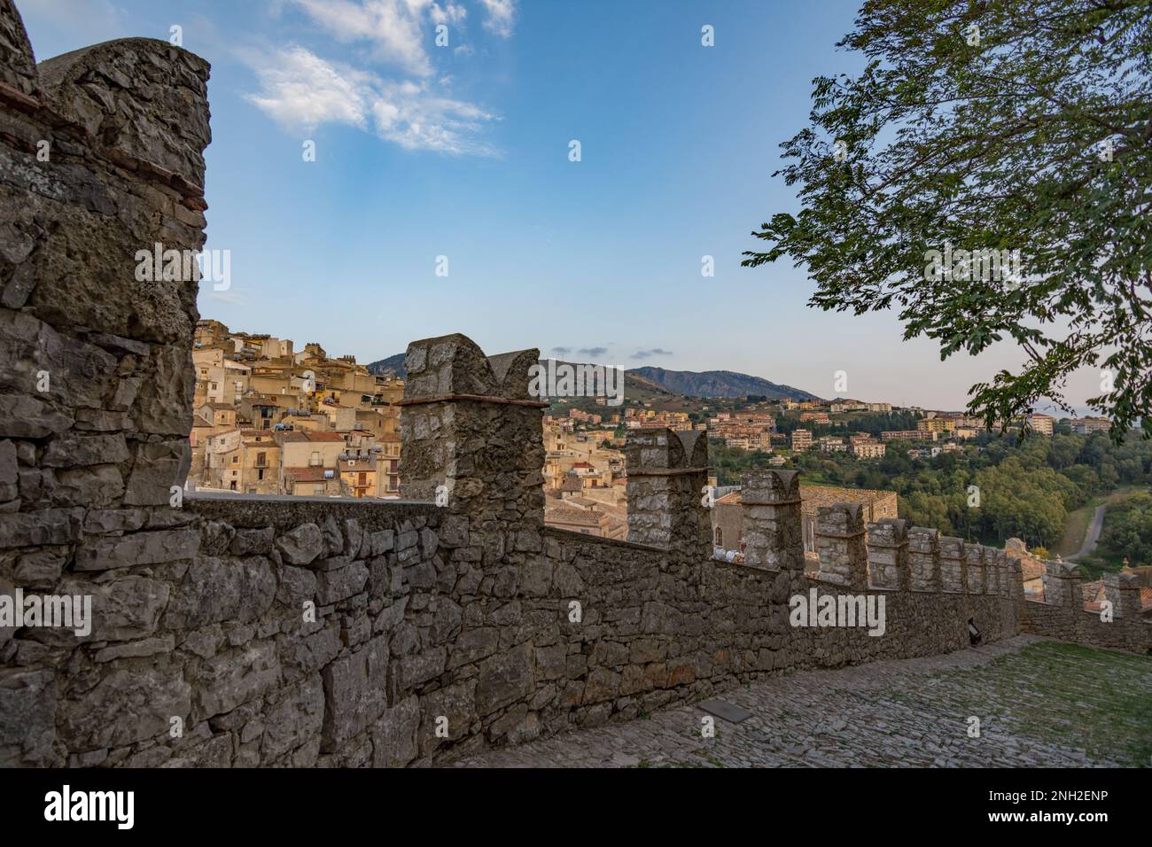 Zinnen verzierte Mauern der Burg Caccamo mit dem Dorf im Hintergrund, Sizilien Stockfoto