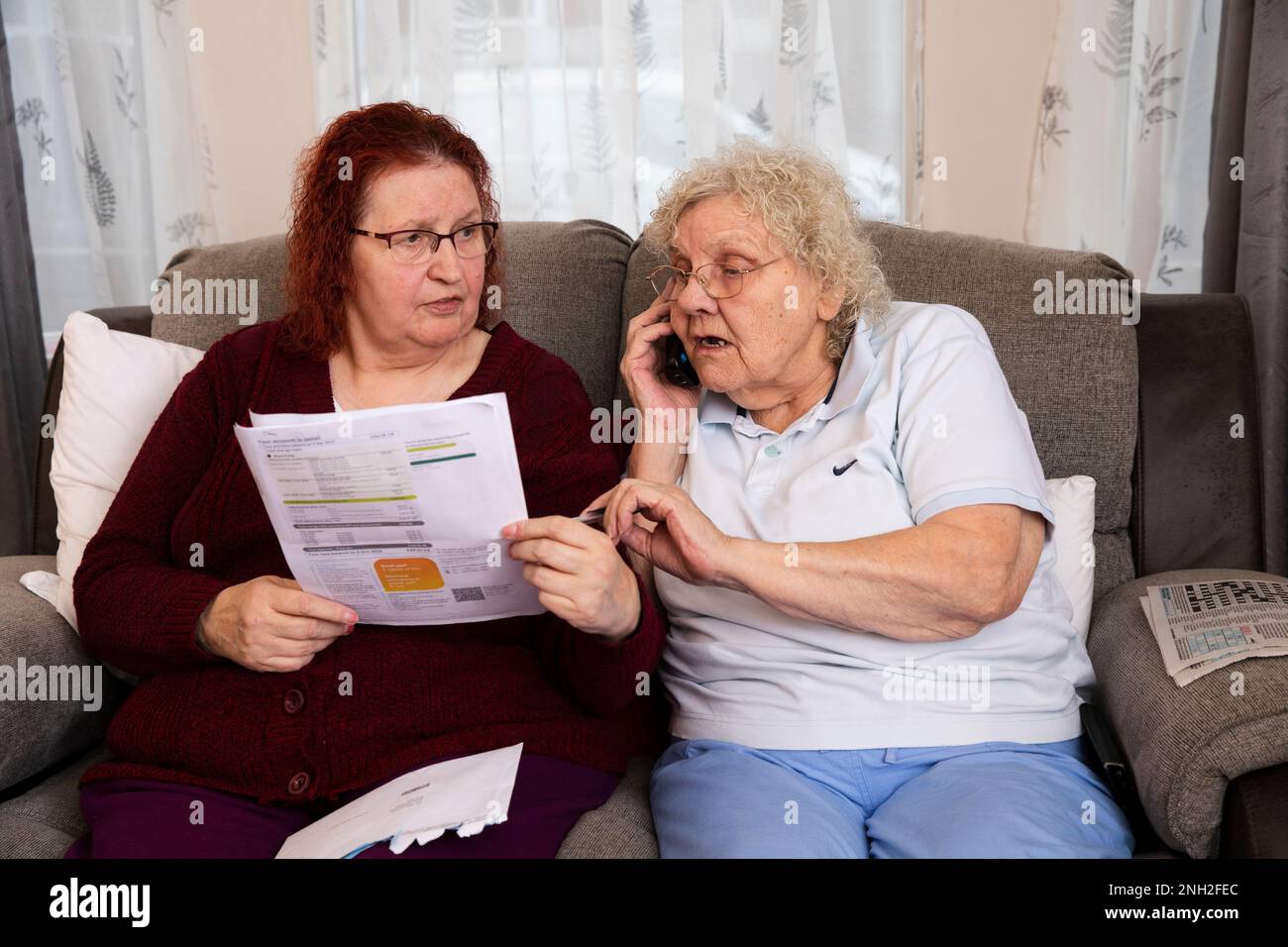 Ältere weibliche Ehepaare, die eine Stromrechnung lesen. Manchester. Vereinigtes Königreich. Stockfoto