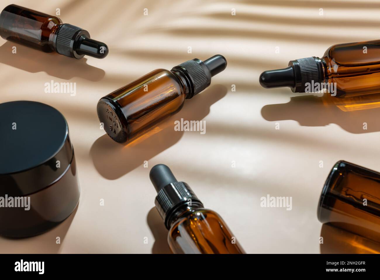 Tropfflaschen aus Glas mit Schönheitsölen oder Serum auf beigefarbenem Hintergrund. Hautpflegeprodukte mit schönem Tageslicht. Trendkonzept Naturkosmetik mit Stockfoto