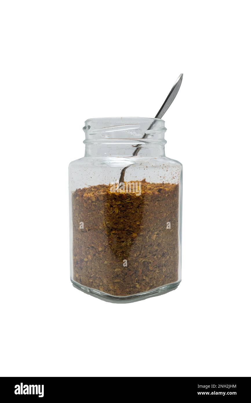 Chilipulver in einem Glasgefäß mit dem Löffel. Isoliert auf weißem Hintergrund mit Beschneidungspfad. Stockfoto