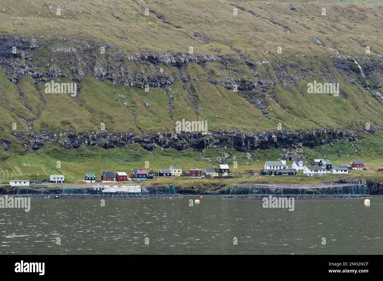 Lachs-Aquakulturkäfige in einer Bucht. Diese Käfige sind in Sicht einer Gemeinde. Stockfoto