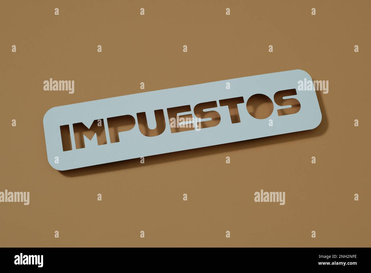 Der Text „Tax“ in spanischer Sprache mit einem hellblauen Schild auf braunem Hintergrund Stockfoto