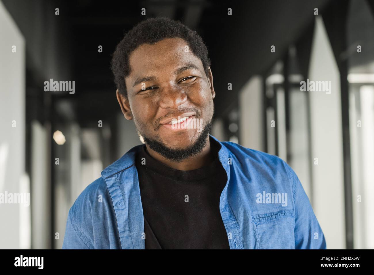 Portrait eines glücklichen afroamerikanischen Kleinunternehmers. Ein junger schwarzer, männlicher Teamleiter, der lächelt, in die Kamera schaut, Mitarbeiter, die in der Moderne arbeiten Stockfoto