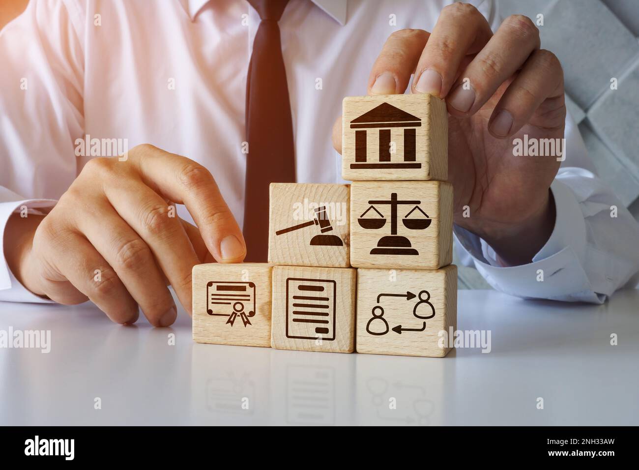 Der Anwalt hält hölzerne Würfel über das Wirtschaftsrecht. Stockfoto