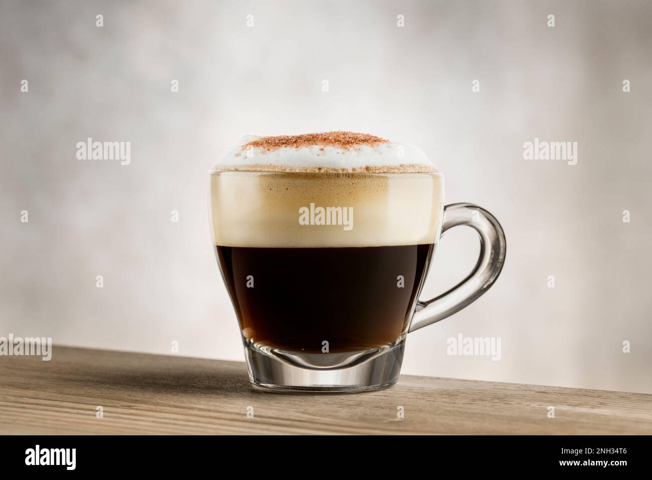 Cappuccino in Glasbecher auf Holztisch Stockfoto