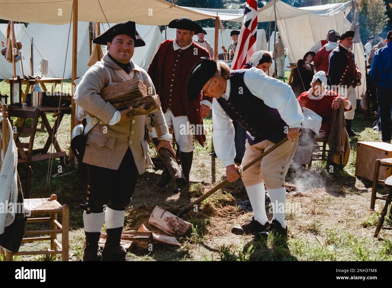 Amerikanische Kolonisten bereiten im Zeltlager während der Nachstellung der Schlacht von Newbury im Unabhängigkeitskrieg eine Feuerstelle vor. Das Bild wurde mit analoger Spalte aufgenommen Stockfoto