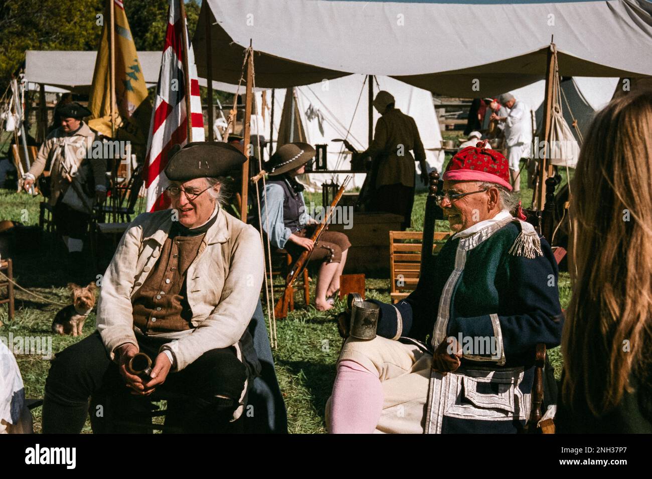 Amerikanische Kolonialsoldaten lachen und reden in einem Zeltlager über eine Feuerstelle während der Nachstellung der Schlacht von Newbury im Unabhängigkeitskrieg. Das Bild war ca. Stockfoto
