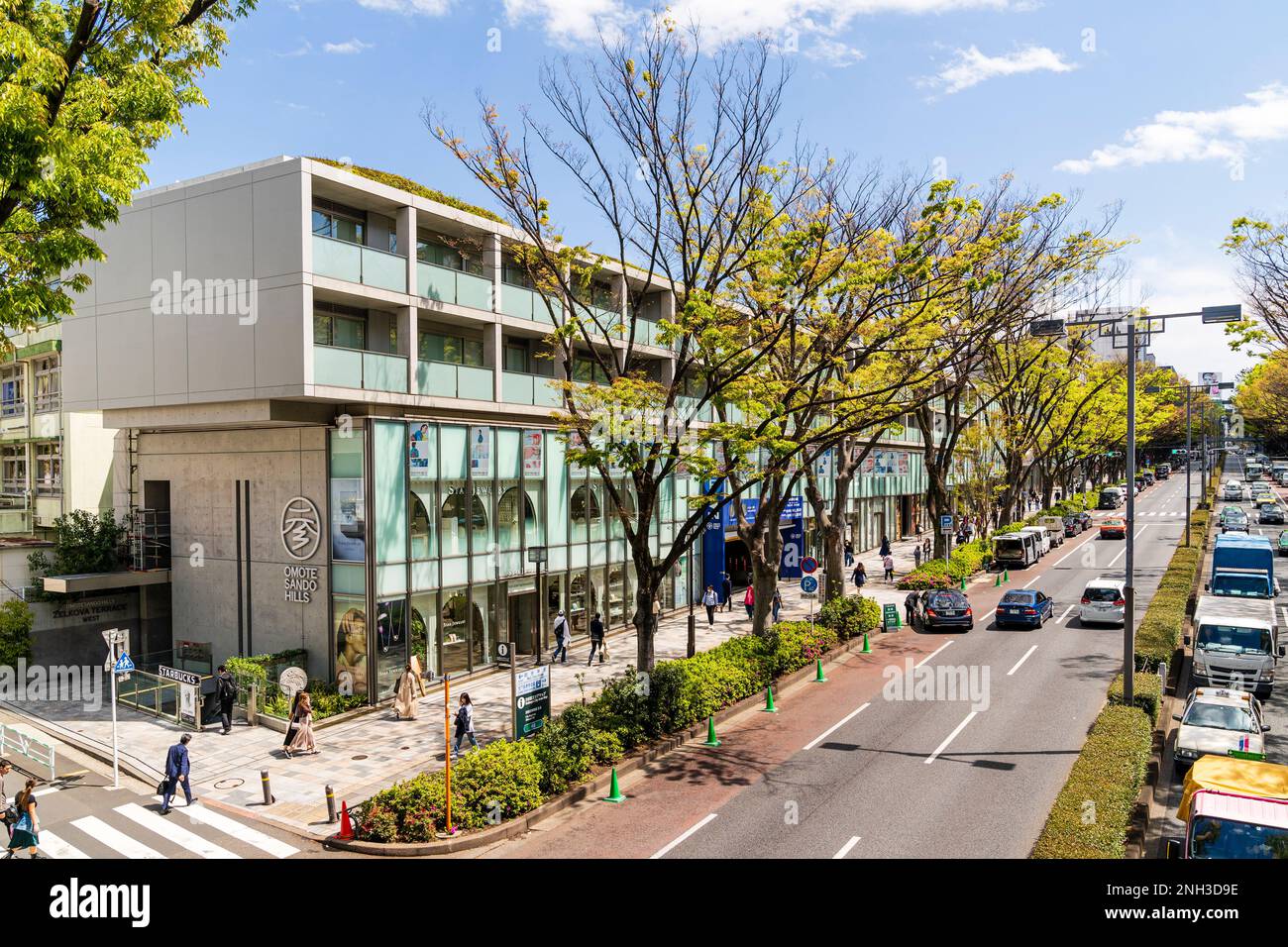 Tokio. Tagsüber Blick entlang Pflaster überfüllt mit Menschen zu Fuß und Äußere der Omotesando Hills Shopping Complex. Blauer Himmel, Frühling. Stockfoto