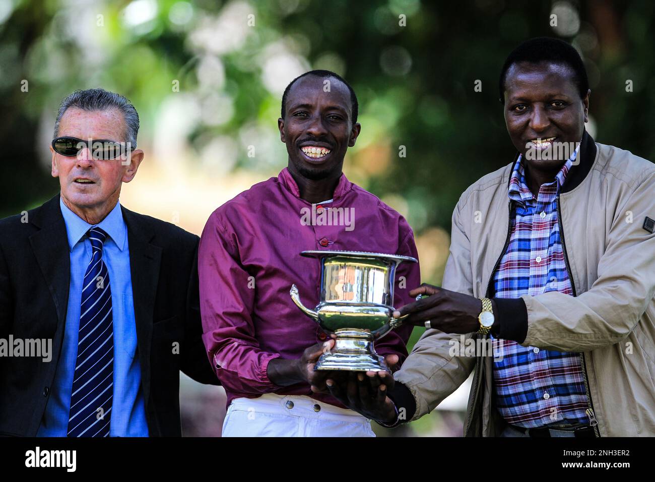 Jockey of Kenya Director Paul Mbugua (rechts) feiert mit Jockey James Muhindi (Zentrum) und Trainer Oliver Gray, der den Chilli Cup hält, das Rennen an Bord von Jack Sparrow auf einer Strecke von 1200m km auf der Ngong Rennbahn in Nairobi, Kenia. Stockfoto