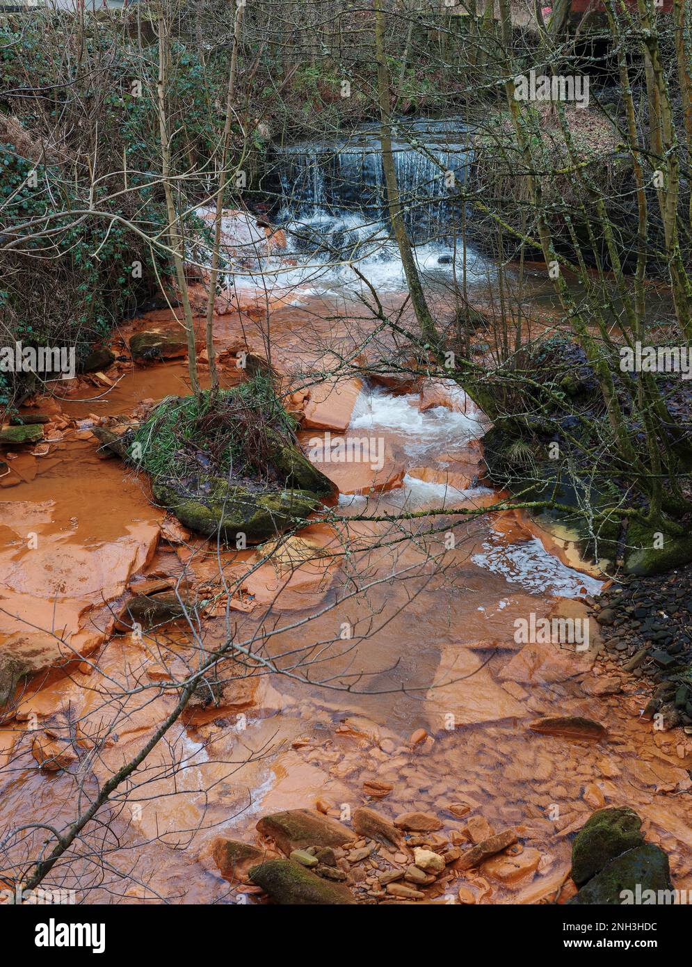 Verschmutztes Flusswasser Felsen, orange gefärbt durch Chemikalien, die flussaufwärts freigesetzt wurden Stockfoto Verschmutztes Flusswasser Felsen, orange gefärbt durch Chemikalien, die flussaufwärts freigesetzt wurden Stockfoto