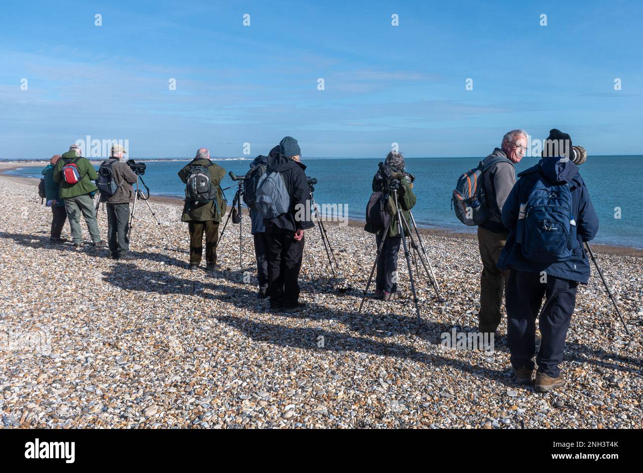 Gruppe von Vogelbeobachtern am Church Norton Beach – Beobachtung von Vögeln mit Teleskopen und Ferngläsern, West Sussex, England, Großbritannien Stockfoto