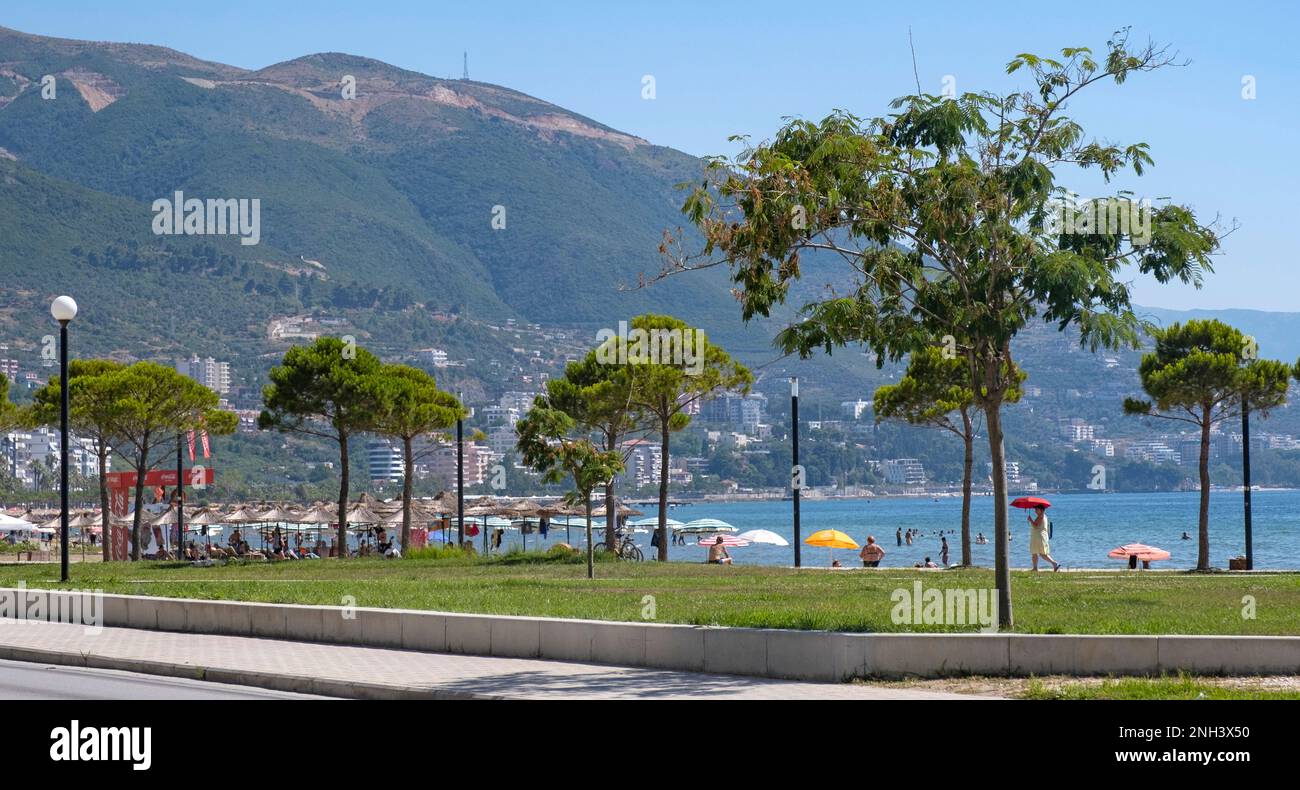 Promenade mit Sonnenanbetern entlang der Bucht von Vlorë im Sommer und der Ceraunianischen Berge im Hinterland von Vlora im Südwesten Albaniens Stockfoto