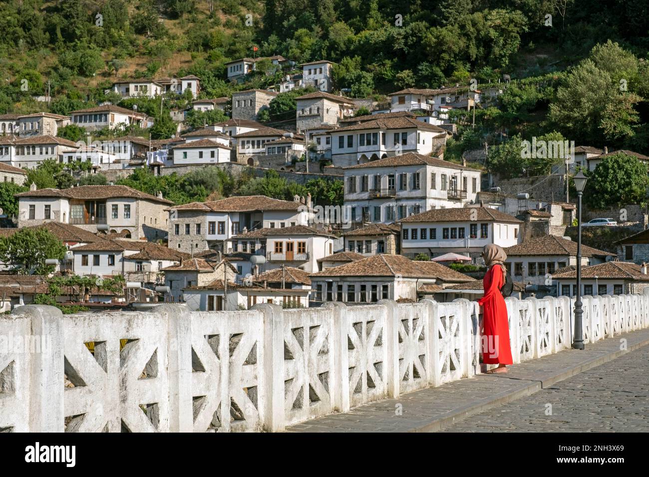 Albanische muslimische Frau/muslima in rotem Kleid und Hijab/Kopftuch auf der Gorica-Brücke über dem Osum-Fluss in der Stadt Berat/Berati, Albanien Stockfoto