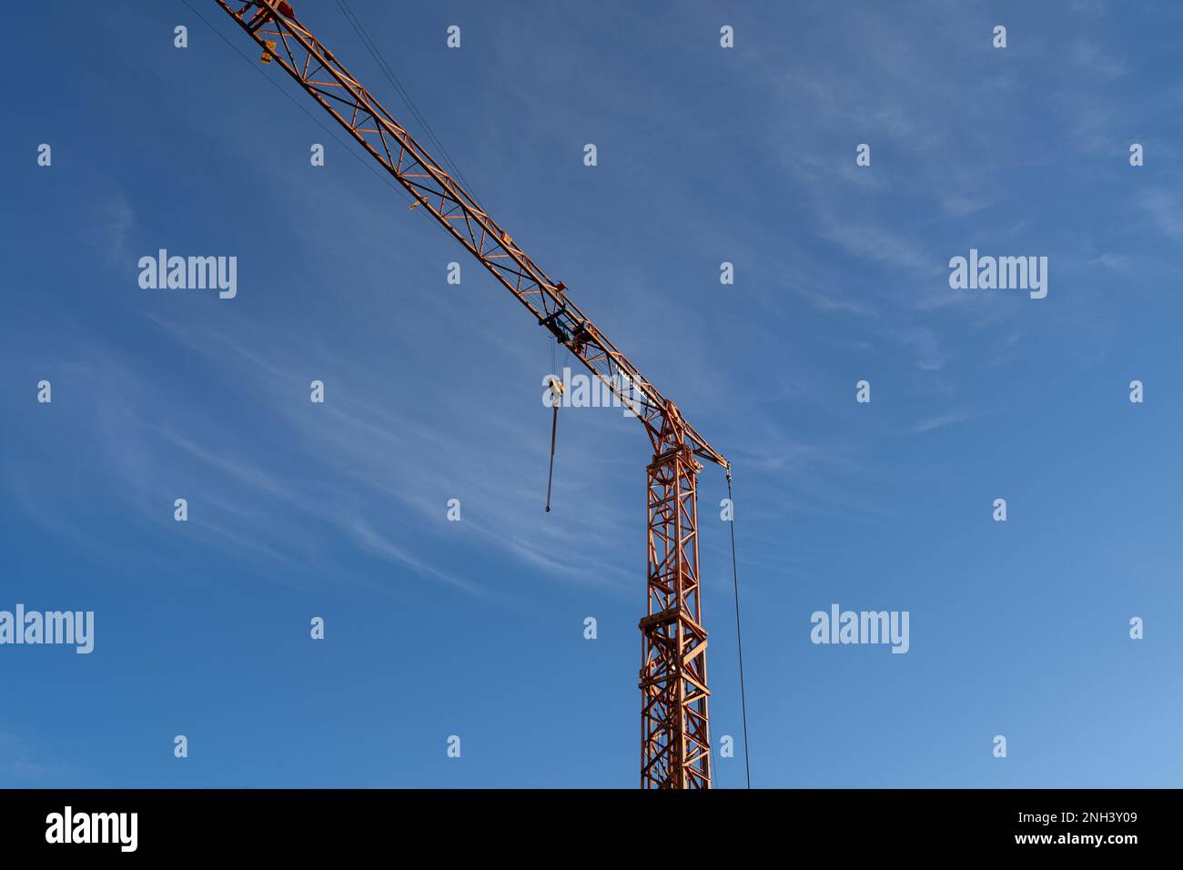 Hoher Baufahrkran mit Haken und einem wunderschönen blauen sonnigen Himmel im Hintergrund Stockfoto