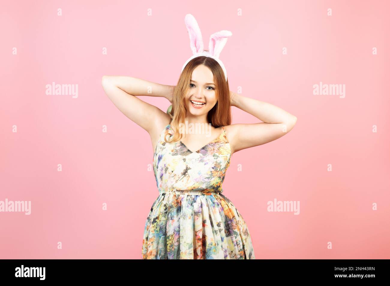 Ein Mädchen in einem bunten Kleid feiert Ostern. Festlich bemalte Eier und ein Lächeln, festliche Hasenohren Stockfoto