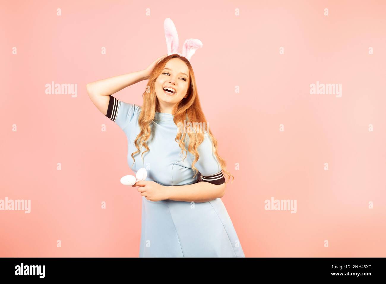 Eine Teenagerin feiert Ostern. Kaninchenohren auf einem Teenager, der Ferieneier hält. Schönes Mädchen feiert Ostern, Tracy. Die Frau lächelt Stockfoto
