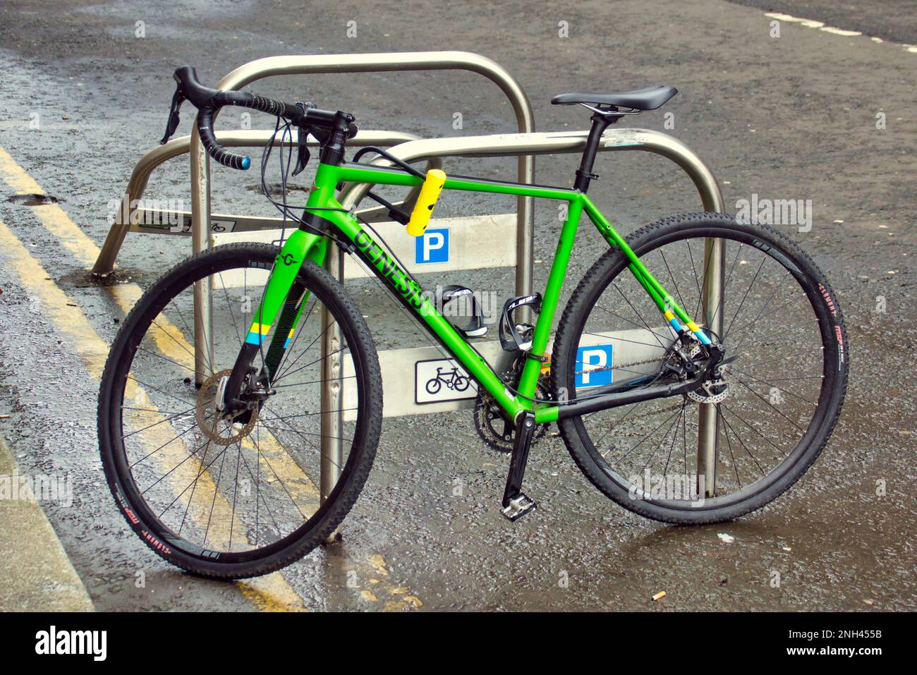 Grünes Fahrrad auf einem Straßenradständer geparkt Stockfoto