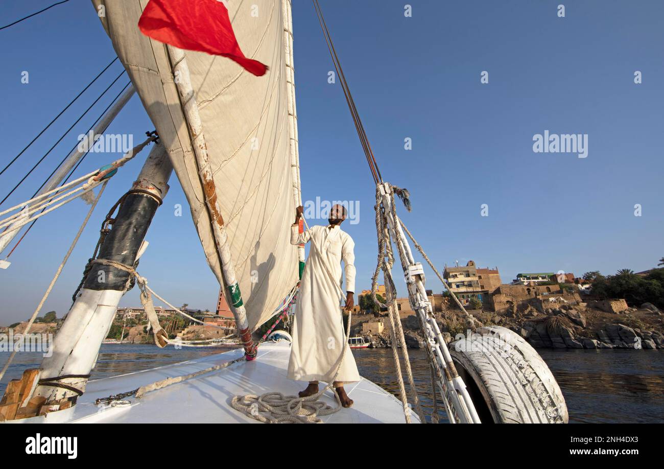 Ein ägyptischer Mann in traditioneller Bootskleidung auf einer Feluke oder einem traditionellen Segelboot auf dem Nil, Assuan, Ägypten Stockfoto