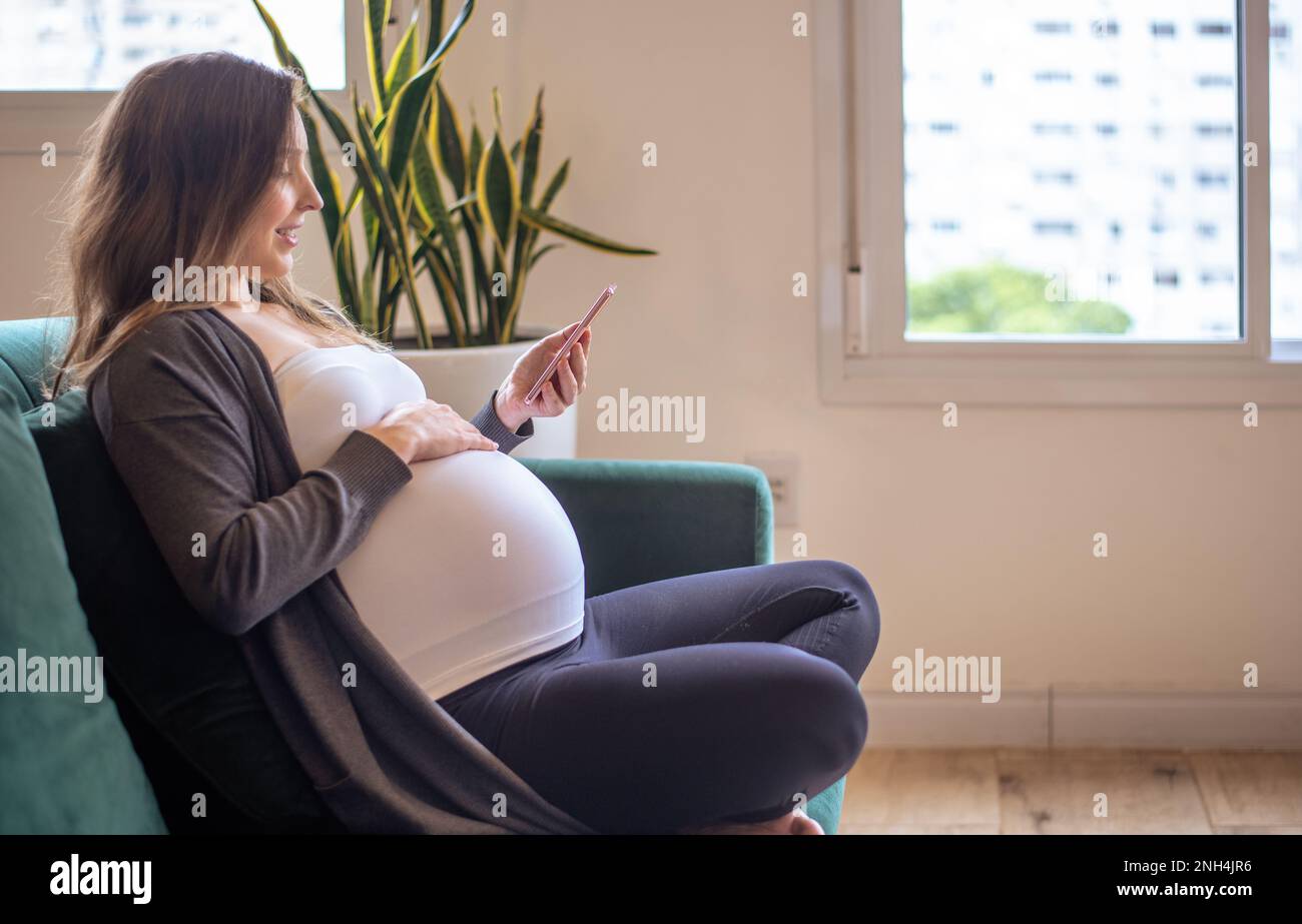 Schwangere Frau, die ein Smartphone benutzt Stockfoto
