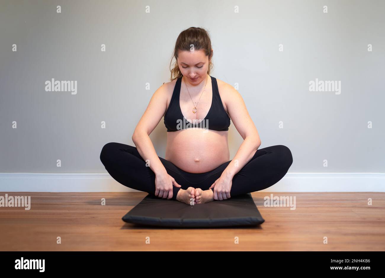Werdende Mutter, die zu Hause Yoga macht Stockfoto