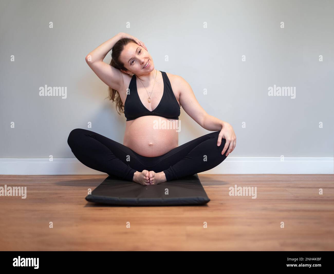 Schwangere Frau dehnt ihre Trapezmuskeln Stockfoto