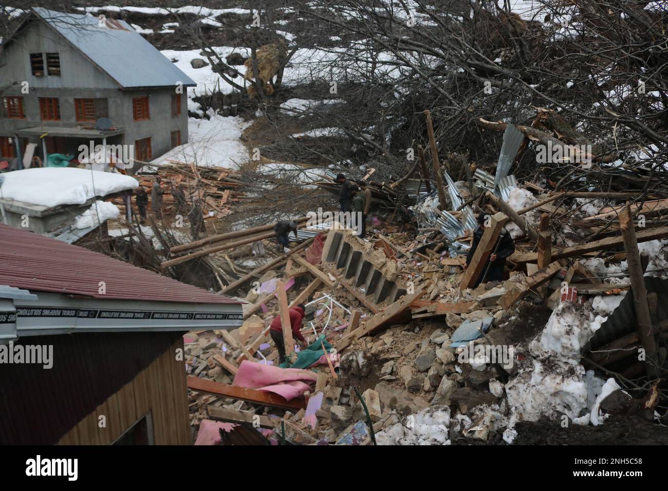 Srinagar, Kaschmir. Februar 20,2023, Srinagar kashmir, indien : Menschen gehen über Trümmer nach einem Erdrutsch in der Gegend von Rezan in Sonamarg, Ganderbal, mindestens 10 Häuser, mehrere Geschäfte und vier Kuhställe wurden beschädigt, nachdem über Nacht ein Erdrutsch in die Gegend von Rezan fiel. Die Autobahn Srinagar-Leh wurde geschlossen. Weitere Erdrutsche ereigneten sich in der Gegend von Duksar Dalwa in Ramban mit 13 beschädigten Häusern. Februar 20,2023, Srinagar kaschmir, indien. ( Foto Von Firdous Nazir/Eyepix Group) Kredit: Eyepix Group/Alamy Live News Stockfoto