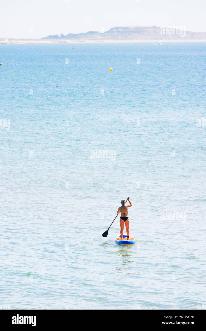 BOURNEMOUTH, Großbritannien - 08. Juli 2022. Reife Frau oder Frau mittleren Alters mit grauem Haar vor der Dorset-Küste. Mit Isle of Wight am Horizont Stockfoto