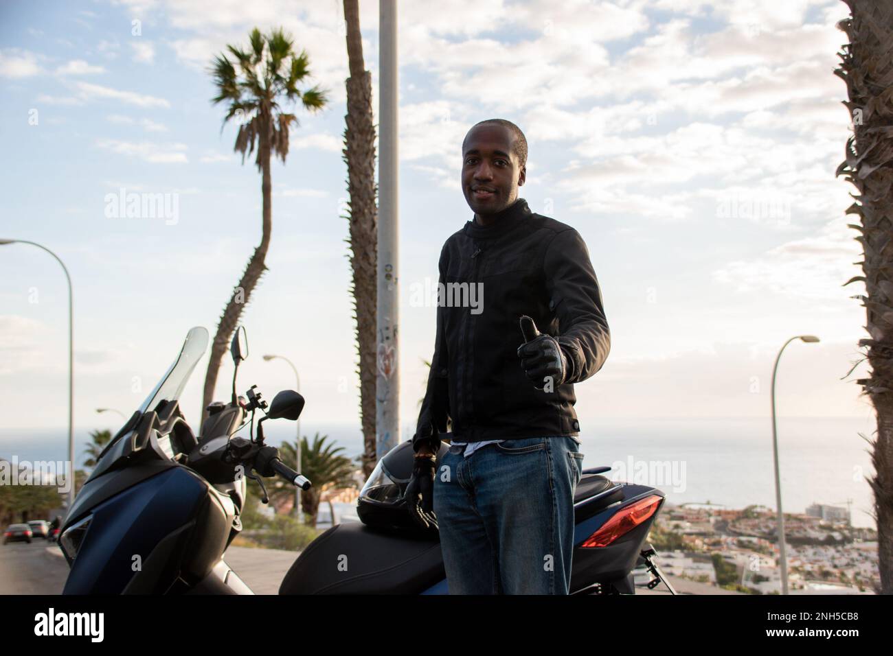 Afroamerikanischer Biker, der den Daumen nach oben zeigt und Motorradausrüstung mit Schutz trägt Stockfoto