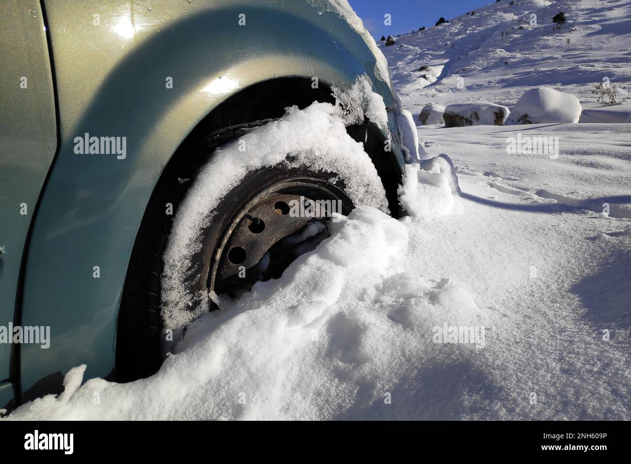Nahaufnahme des Vorderrads eines Autos, das im Schnee feststeckt. Stockfoto