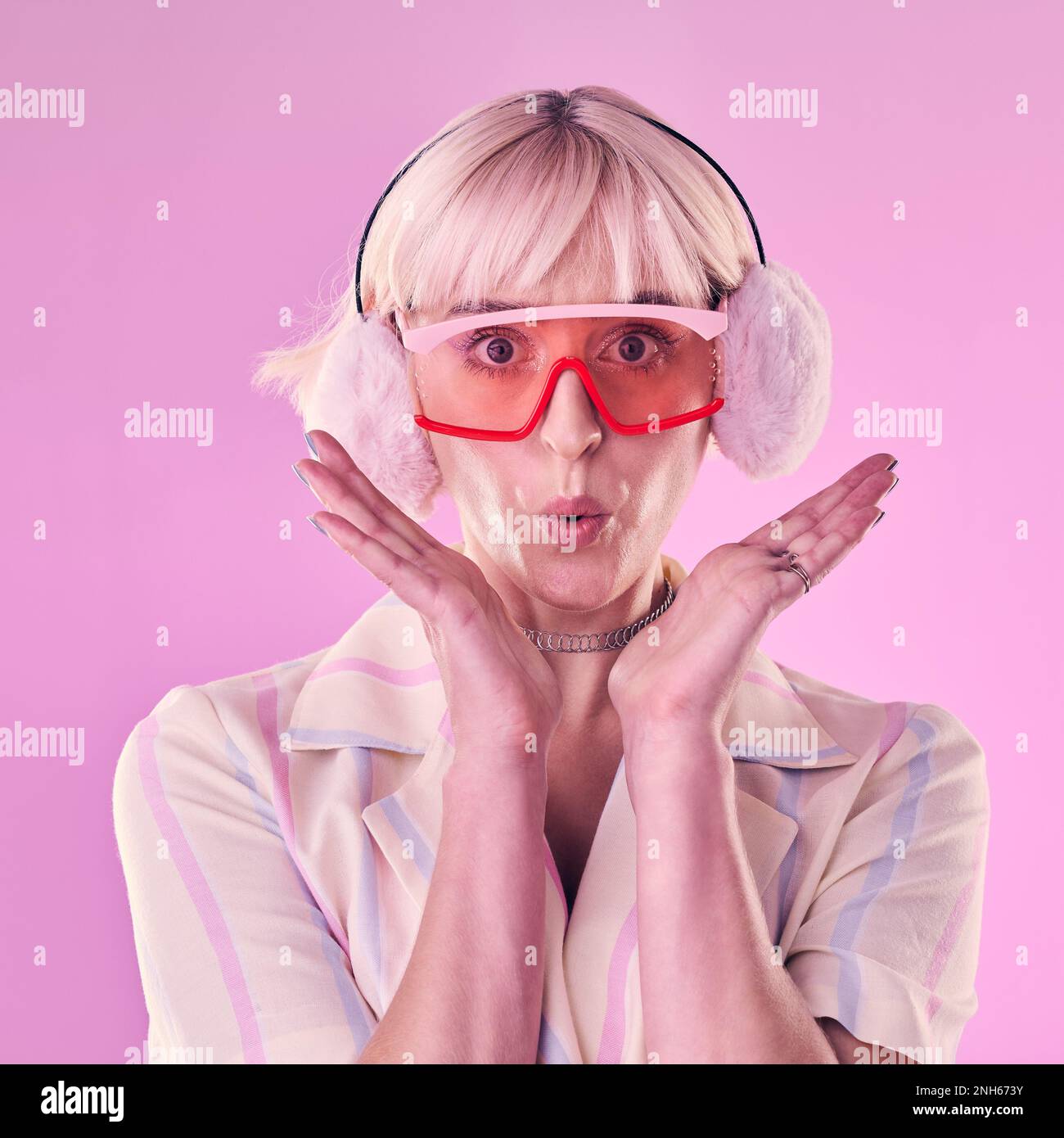 Mode, Porträt und eine Frau im Studio für Wow, Überraschung und Comic auf pinkfarbenem Hintergrund. Ästhetische Modellperson mit Brille und Ohrenschützer Stockfoto