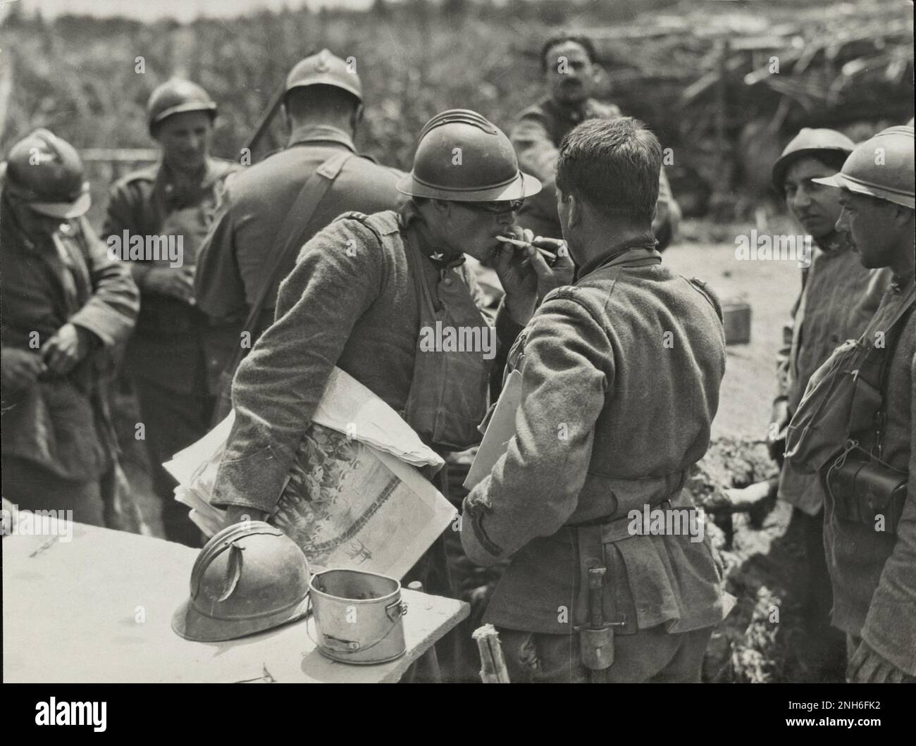 Erster Weltkrieg Ein italienischer Soldat, der eine illustrierte Zeitung hält, lässt seine Zigarette von einem anderen Soldaten in der Nähe des Piave River in Italien entzünden. Oktober 1918 Stockfoto