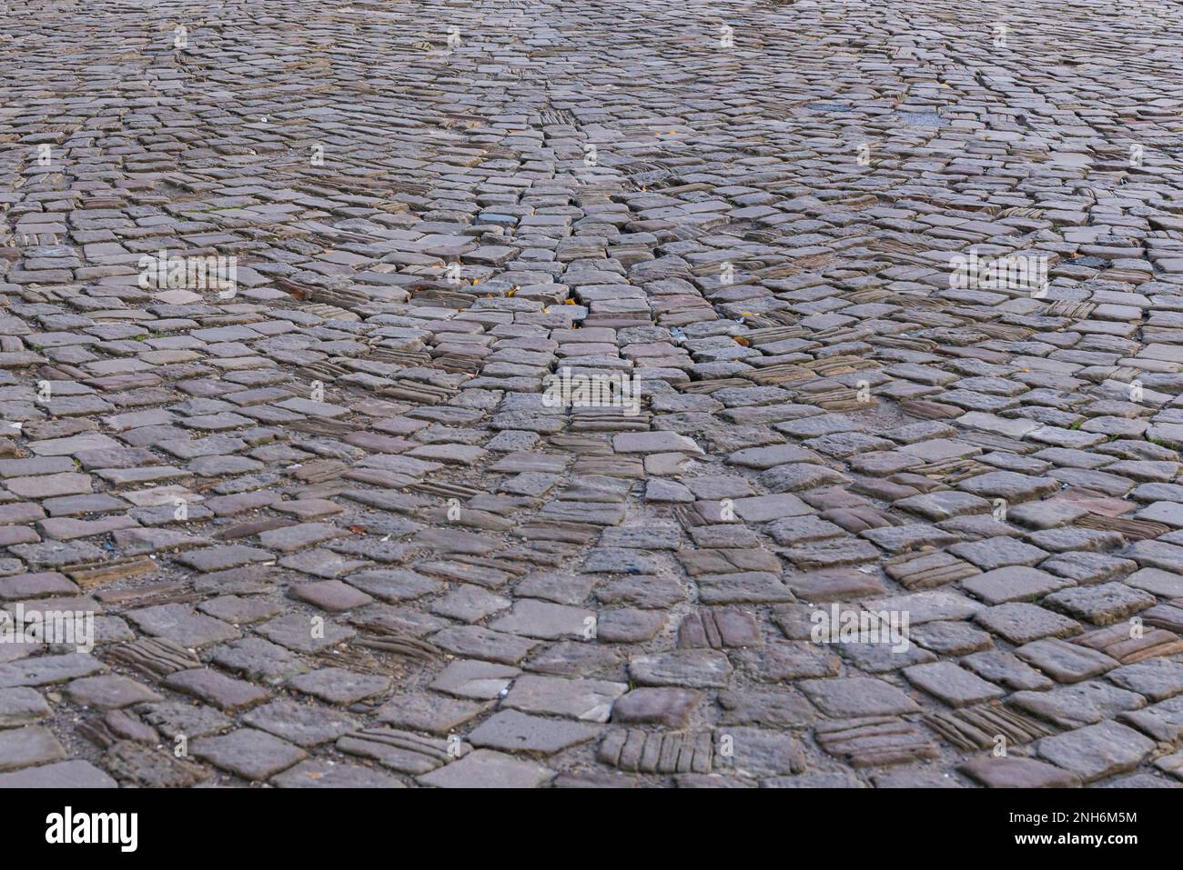 Blick von oben auf eine alte gepflasterte Straße mit Kopfsteinpflaster. Nahaufnahme des Hintergrunds. Stockfoto