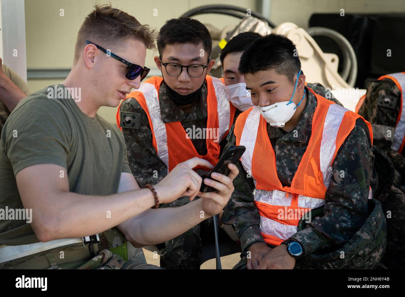 USA Air Force Airman 1. Class Preston Finch, ein Auszubildender für Bauwesen, zeigt Mitgliedern der Republik Korea Air Force Bilder von Bauprojekten, die er in der Vergangenheit während einer Schulung zur schnellen Reparatur von Flugplatzschäden am 20. Juli 2022 am Luftwaffenstützpunkt Gwangju, Republik Korea, abgeschlossen hat. Während der kombinierten Ausbildung konnten die Mitglieder der USAF und der ROKAF ihre Fähigkeiten zur schnellen Reparatur von Flugplatzschäden verbessern, indem sie von den unterschiedlichen Techniken der anderen lernten. Stockfoto USA Air Force Airman 1. Class Preston Finch, ein Auszubildender für Bauwesen, zeigt Mitgliedern der Republik Korea Air Force Bilder von Bauprojekten, die er in der Vergangenheit während einer Schulung zur schnellen Reparatur von Flugplatzschäden am 20. Juli 2022 am Luftwaffenstützpunkt Gwangju, Republik Korea, abgeschlossen hat. Während der kombinierten Ausbildung konnten die Mitglieder der USAF und der ROKAF ihre Fähigkeiten zur schnellen Reparatur von Flugplatzschäden verbessern, indem sie von den unterschiedlichen Techniken der anderen lernten. Stockfoto