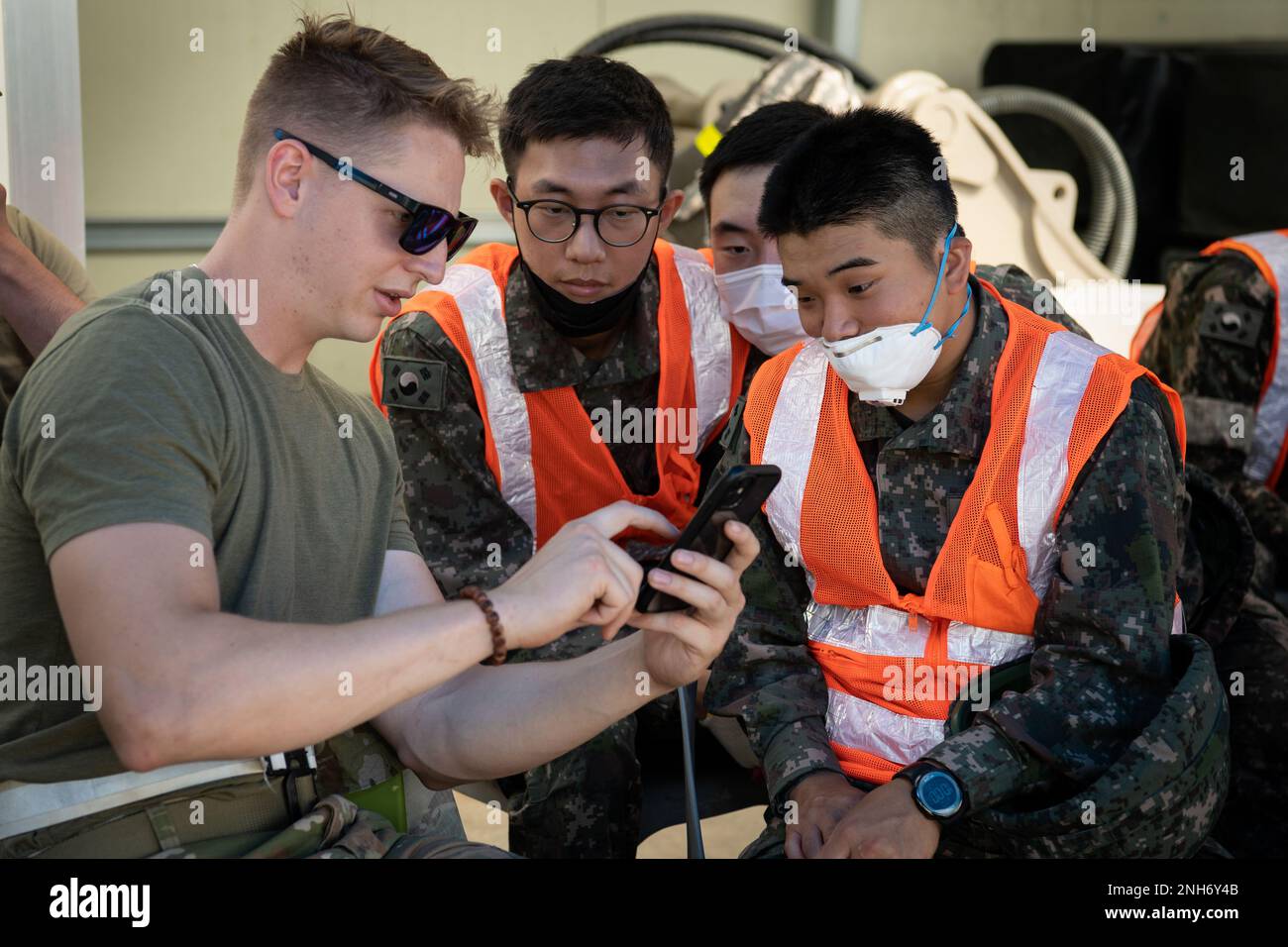 USA Air Force Airman 1. Class Preston Finch, ein Auszubildender für Bauwesen, zeigt Mitgliedern der Republik Korea Air Force Bilder von Bauprojekten, die er in der Vergangenheit während einer Schulung zur schnellen Reparatur von Flugplatzschäden am 20. Juli 2022 am Luftwaffenstützpunkt Gwangju, Republik Korea, abgeschlossen hat. Während der kombinierten Ausbildung konnten die Mitglieder der USAF und der ROKAF ihre Fähigkeiten zur schnellen Reparatur von Flugplatzschäden verbessern, indem sie von den unterschiedlichen Techniken der anderen lernten. Stockfoto