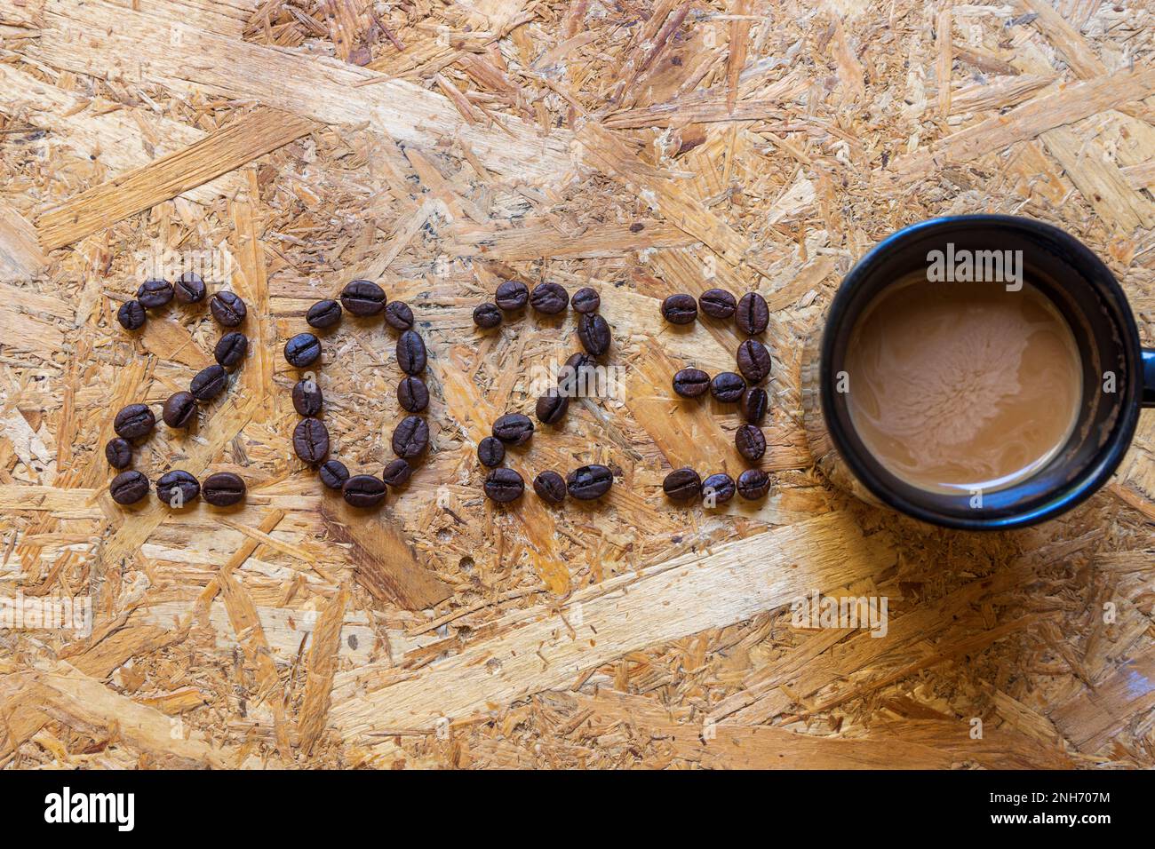 2023 Zahl aus Kaffeebohnen mit einer Tasse Kaffeemilch. Platz für Text kopieren Stockfoto