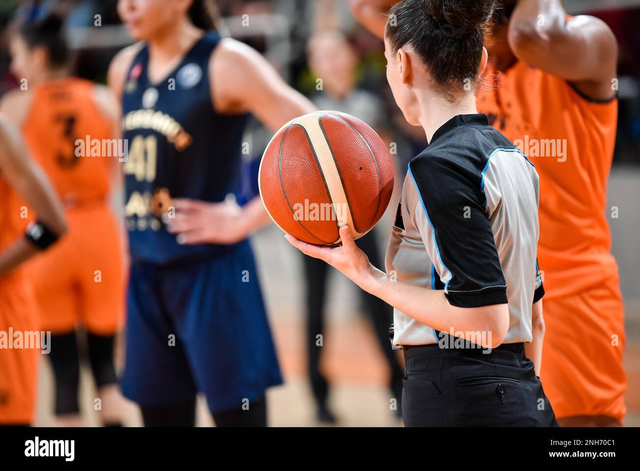 Die Schiedsrichterin hält den Ball während des Basketballspiels. Stockfoto