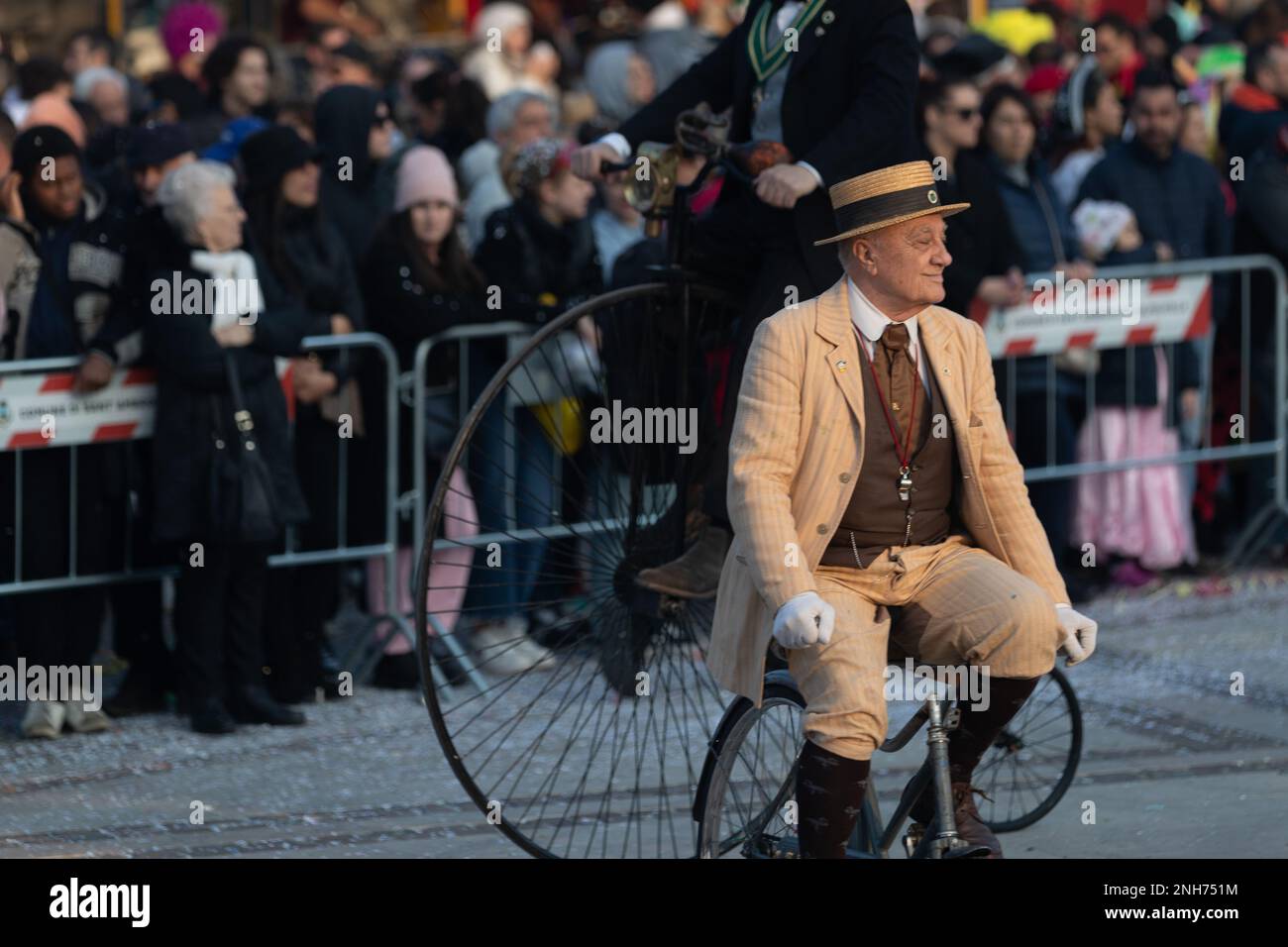 Antique Bicycle Adventure: Karnevalsbesucher fahren auf einer Penny Farthing durch die Menschenmassen Stockfoto