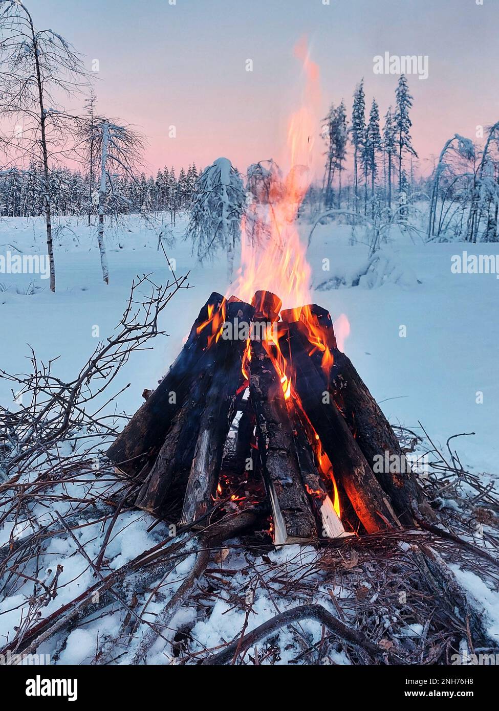 Lagerfeuer in schwedischer Winterlandschaft in der Dämmerung. Stockfoto