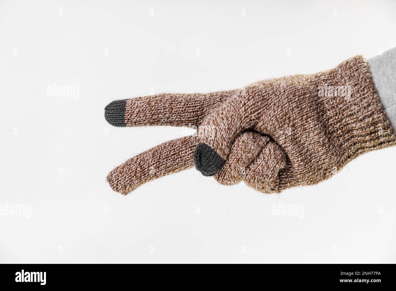 Gesten des Symbols des Friedens und Sieges mit zwei Fingern einer Hand in warmen Winterhandschuhen auf weißem Hintergrund Stockfoto