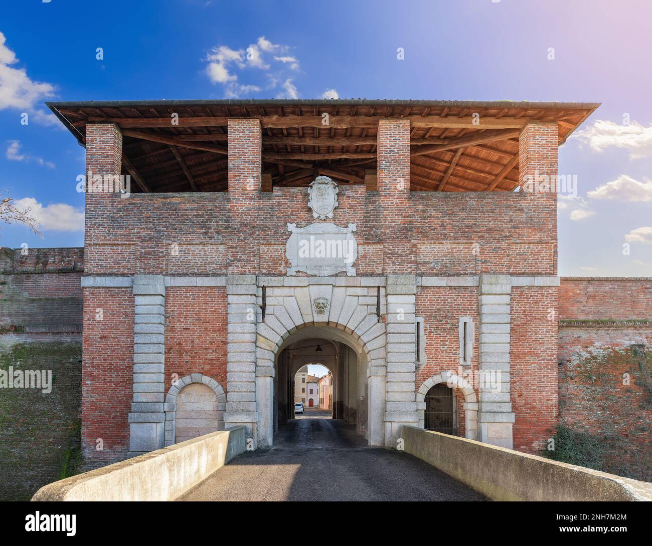 Die Ziegelfassade und der rustizierte Marmorbogen von Porta Vittoria bilden einen befestigten Eingang nach Sabbioneta, Lombardei, Italien, unter einem blauen Himmel. Stockfoto