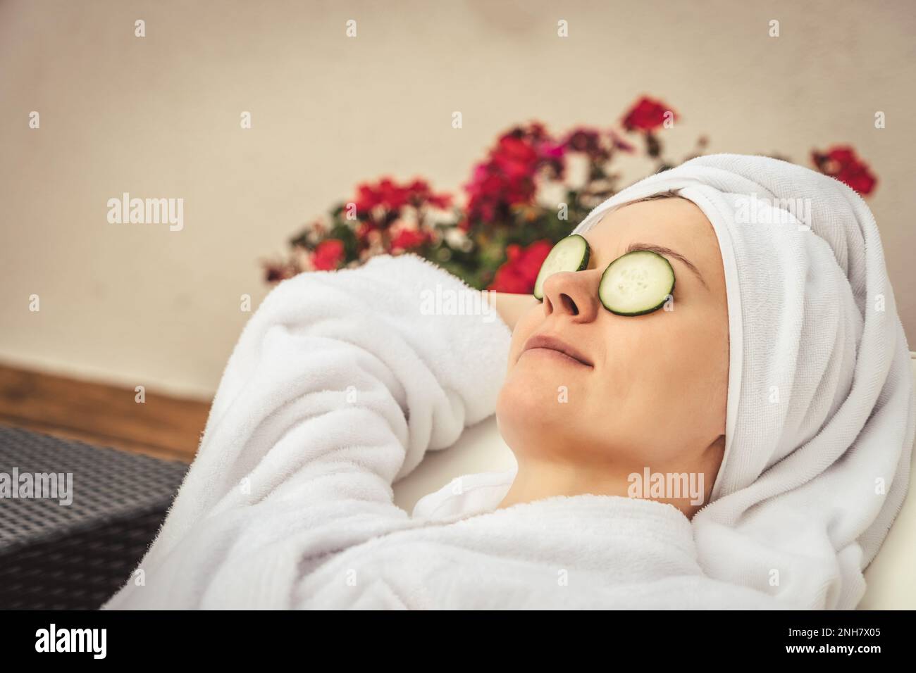 Entspannte junge Frau, die mit Gurken in der Natur behandelt wird, im luxuriösen Spa-Resort. Wellness- und Heilkonzept. Stockfoto