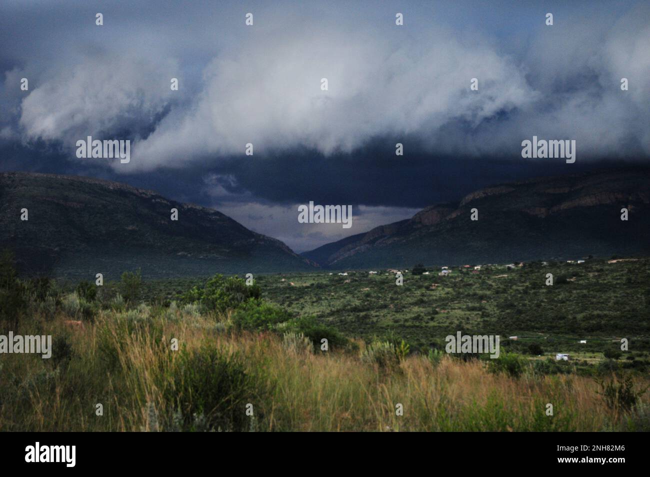 Gewitterwolken sammeln sich über einem afrikanischen Dorf, während Teile des Südostens Afrikas von extremen Wetterbedingungen heimgesucht werden Stockfoto