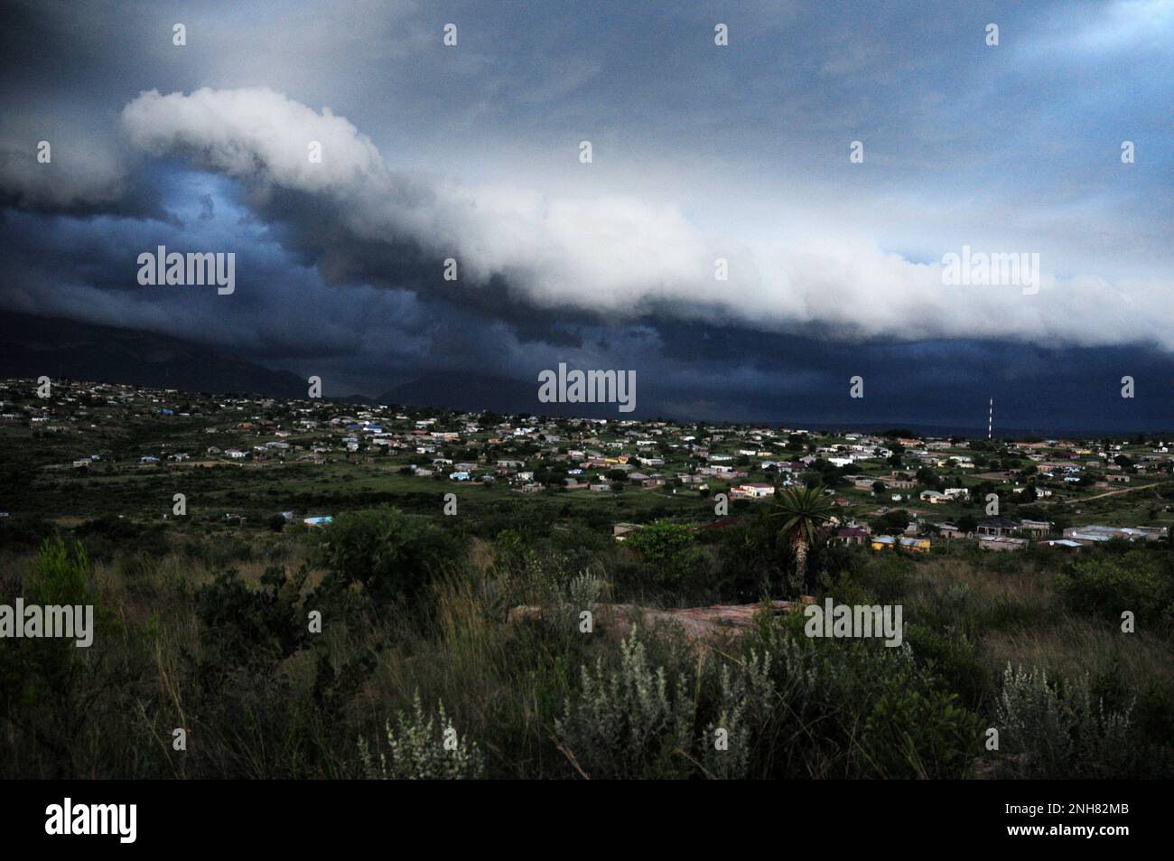 Gewitterwolken sammeln sich über einem afrikanischen Dorf, während Teile des Südostens Afrikas von extremen Wetterbedingungen heimgesucht werden Stockfoto