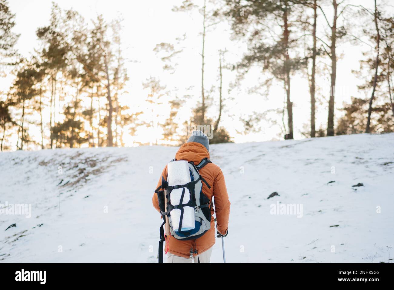 Mann mit Rucksack Trekking in den Bergen. Kaltes Wetter, Schnee auf Hügeln. Winterwandern. Stockfoto