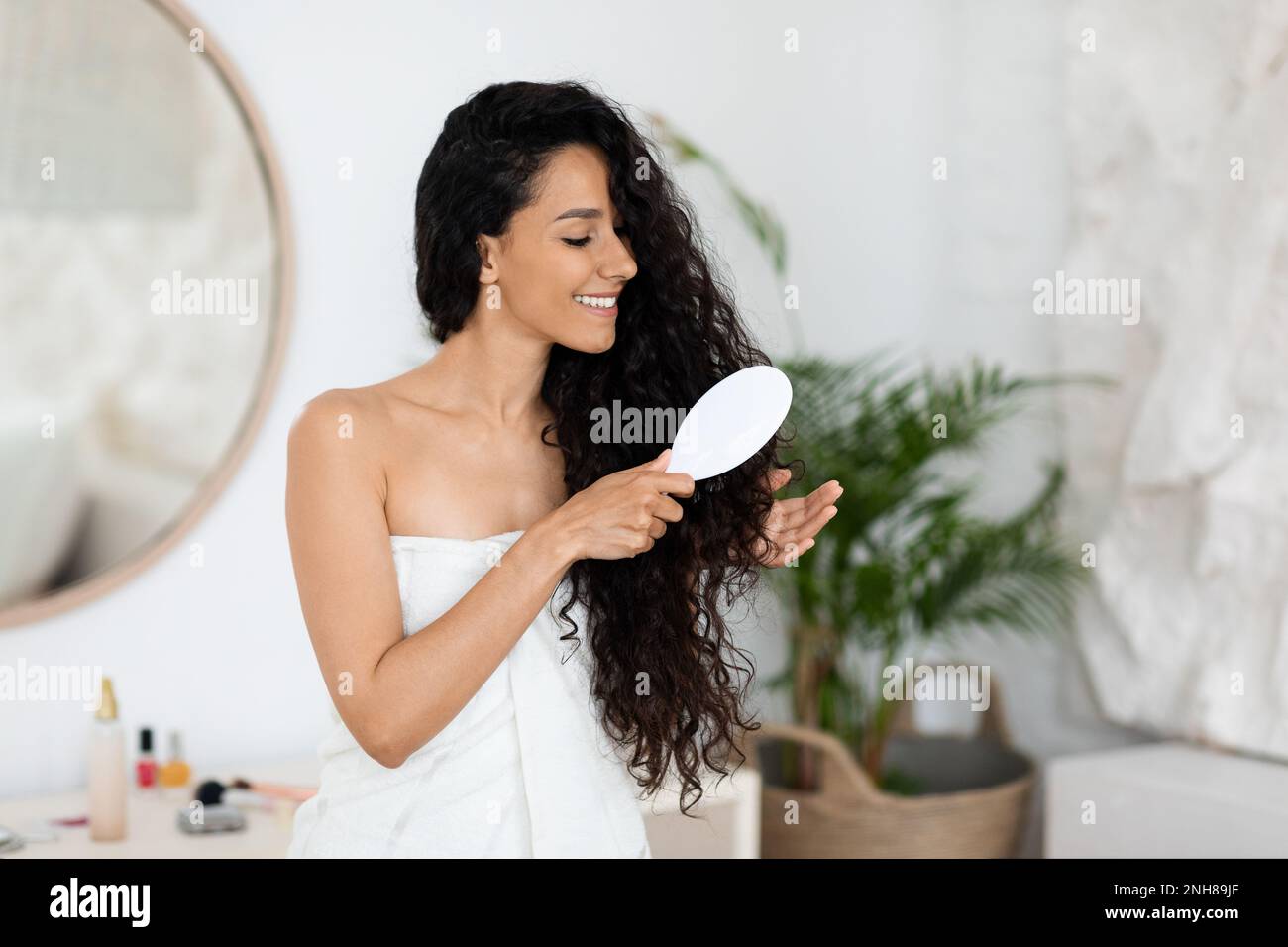 Fröhliche, weiße Jungfrau im Handtuch, die lange Locken kämmt, genießen Sie  eine Spa-Behandlung Stockfotografie - Alamy