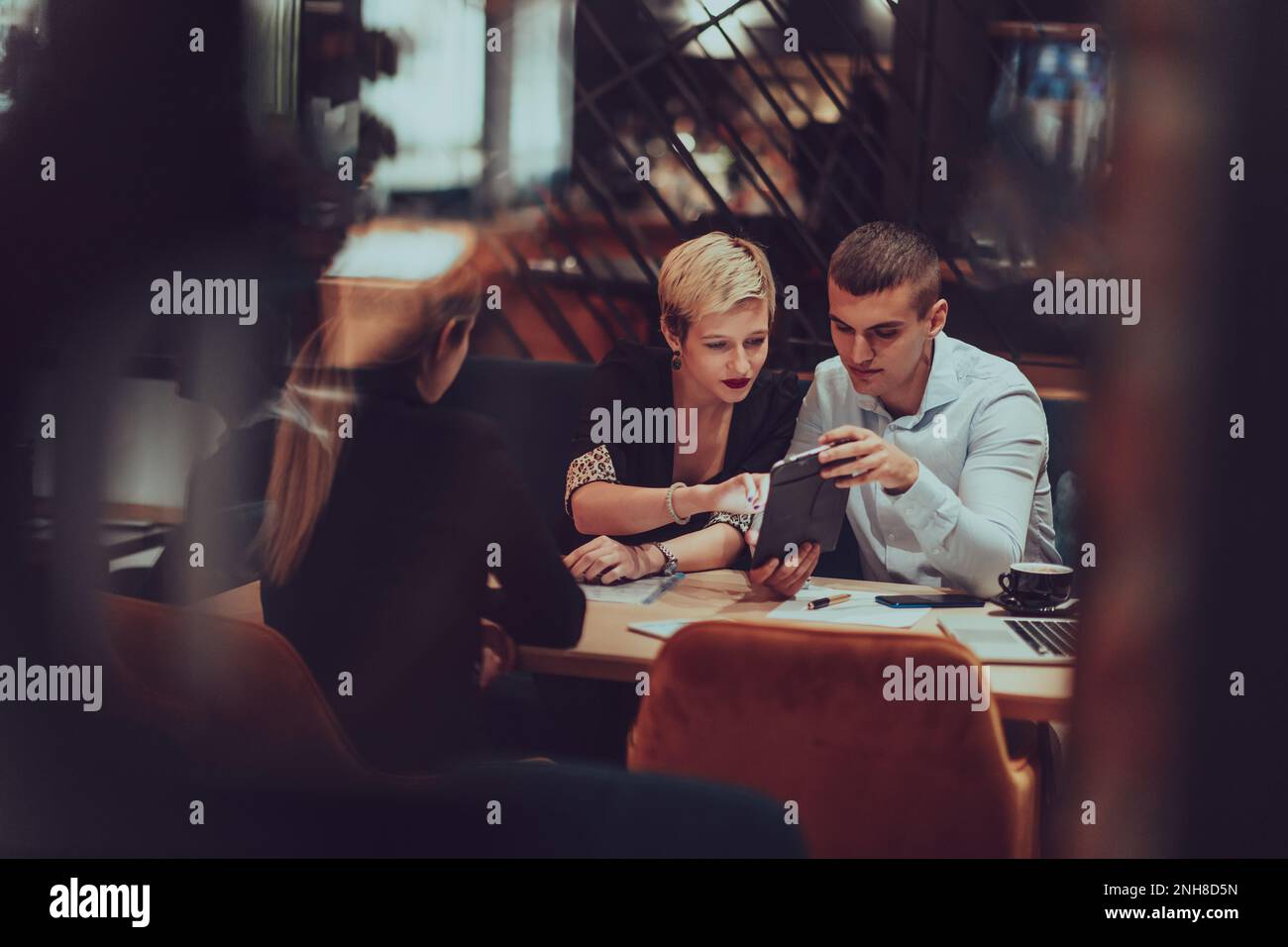 Foto durch das Glas einer Gruppe von Geschäftsleuten, die in einem Café sitzen und Geschäftspläne und Ideen für neue kommerzielle Online-Services besprechen Stockfoto